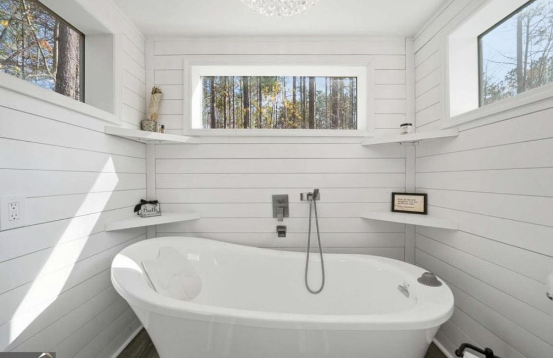 Deep freestanding spa soaking tub with forest windows